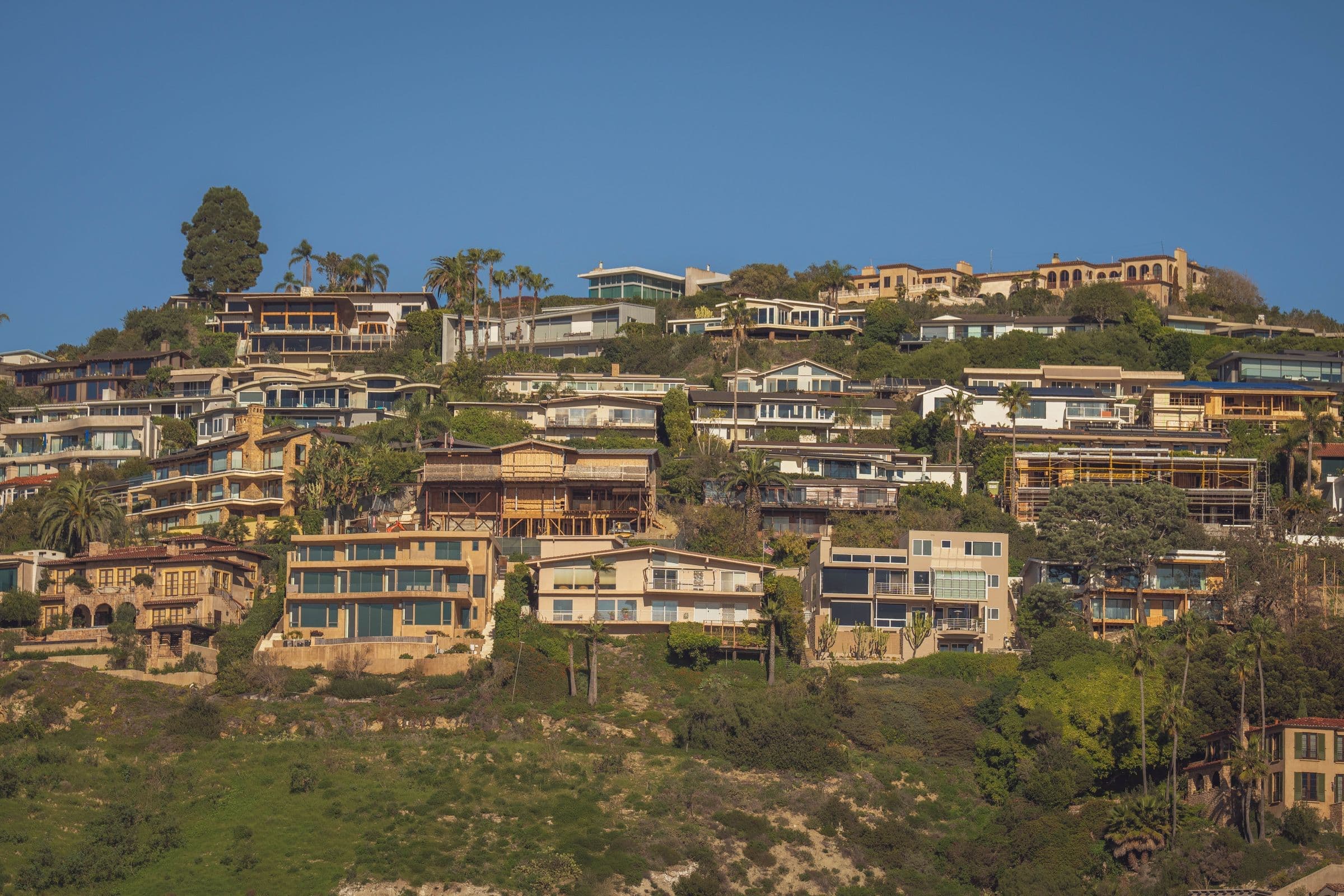 Scenic view of modern hillside homes with lush greenery and blue sky backdrop, the kind of North County setting our movers work in around Hidden Meadows, CA