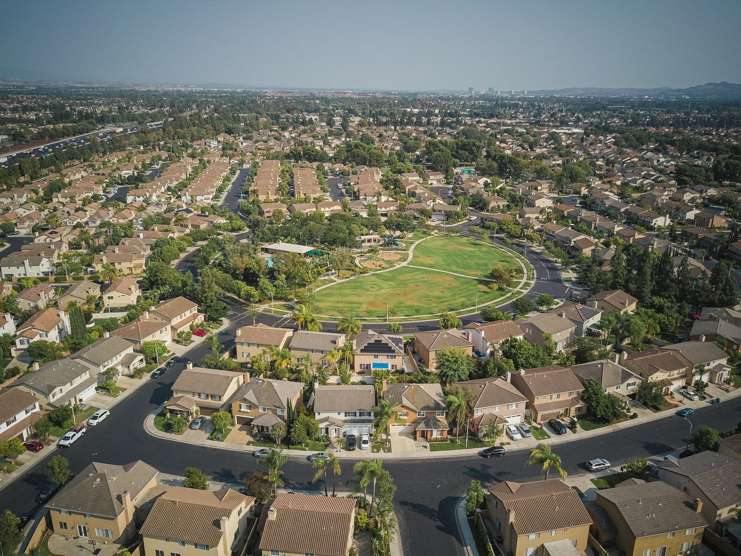 Drone aerial view of a spacious suburban neighborhood with a central park area, the kind of North County setting our movers work in around Poway, CA